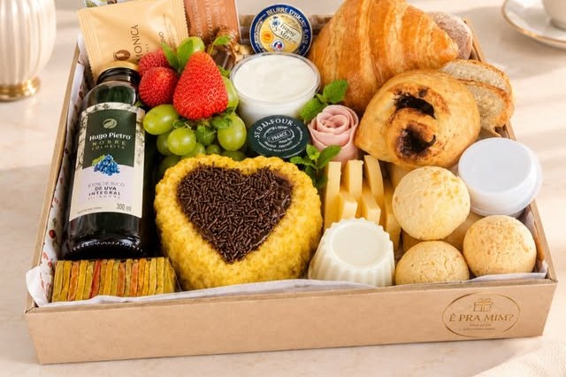 Cesta de café da manhã com croissants, frutas e doces em caixa de madeira